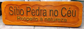 Placa de madeira pinus com o texto "Sítio Pedra no Céu, Respeito à natureza" entalhado em letras de alto relevo