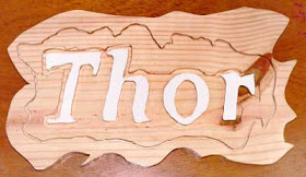 Placa de madeira pinus com bordas orgânicas e o nome "Thor" entalhado em baixo relevo e pintado de branco