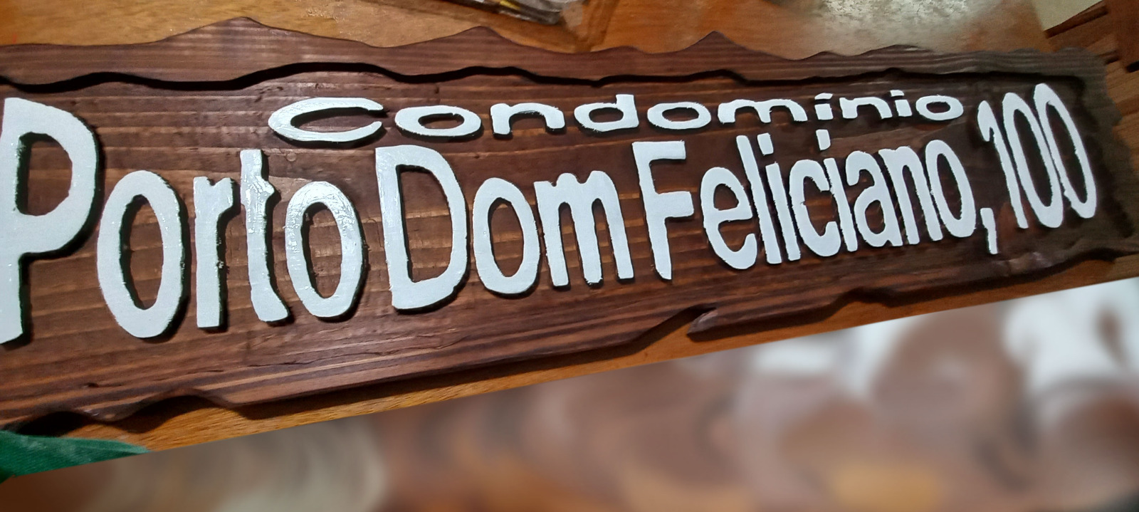 Placa de madeira de pinus entalhada para o Condomínio Porto Dom Feliciano, 100, com letras em alto relevo pintadas em branco sobre fundo tonalizado, feita para Porto Alegre/RS