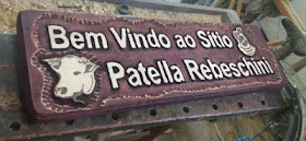 Detalhe em perspectiva da placa Patella Rebeschini mostrando a profundidade das letras em alto relevo e o logotipo pirografado