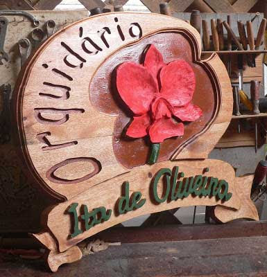 Placa brasão redonda em madeira maciça especial com orquídea esculpida em alto relevo pintada em vermelho e faixa entalhada "Itza de Oliveira", acabamento auto brilho