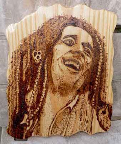 Quadro de madeira maciça de pinus com bordas orgânicas e o retrato do Bob Marley sorrindo, feito em pirografia