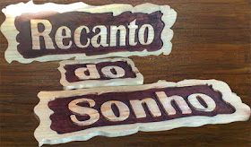 Peças entalhadas em madeira pinus com as palavras "Recanto do Sonho" em letras de alto relevo sobre fundo escurecido com anilina