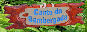 Placa de pinus com bordas orgânicas avermelhadas e o texto "Canto da Sambergada" entalhado em alto e baixo relevo sobre faixa clara