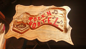 Segundo lado da placa Rock n Hostel, também entalhado em alto relevo com vitrola, notas musicais e letras pintadas