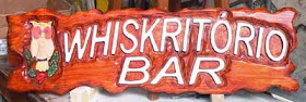 Placa horizontal de pinus com uma coruja pintada e o texto "Whiskritório BAR" entalhado em alto relevo